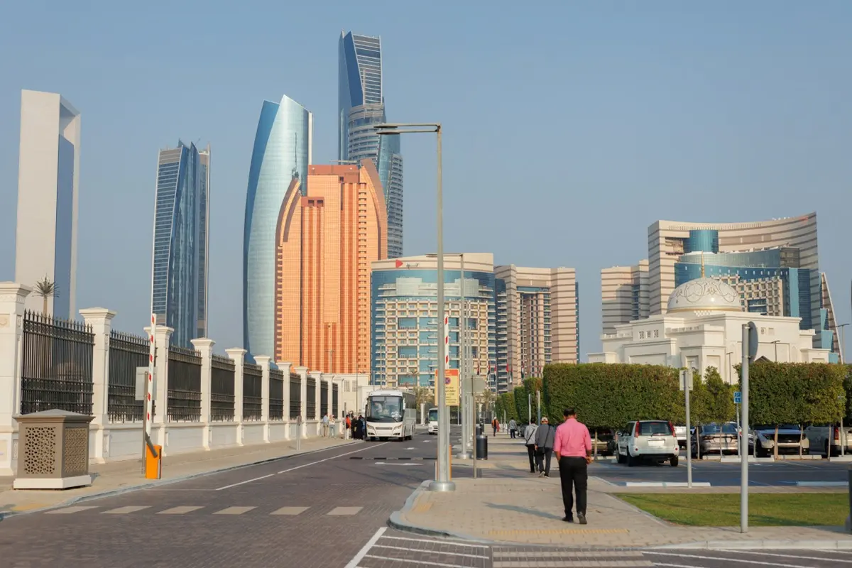 A street in Abu Dhabi between modern towers and a domed building, where the regional connection behind an ADGM structure often lives