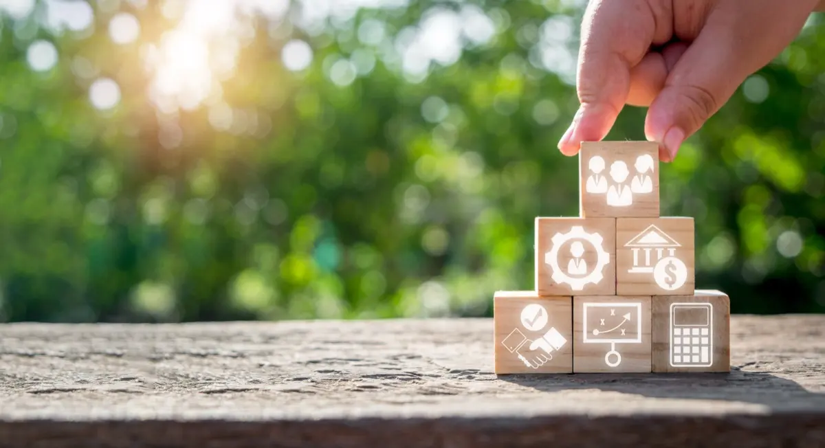 Wooden blocks marked with shareholding icons, the ownership layer an ADGM holding company sits above