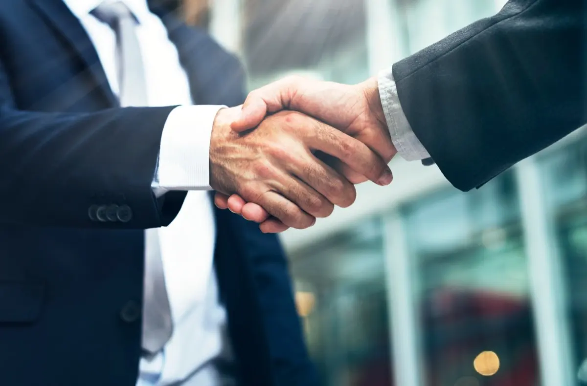 Two business partners shaking hands, the moment a new shareholder joins and the filings begin
