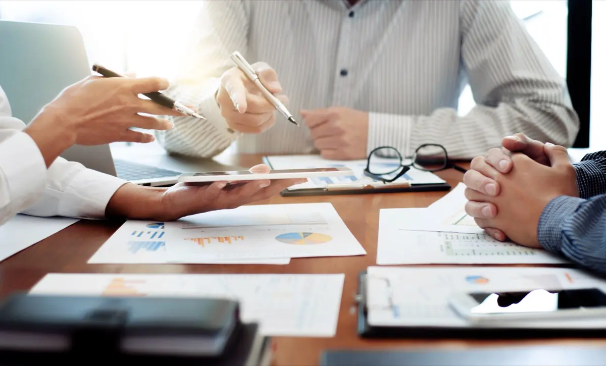 Advisers reviewing charts and figures across a table, the analysis behind a fund's corporate tax exemption application