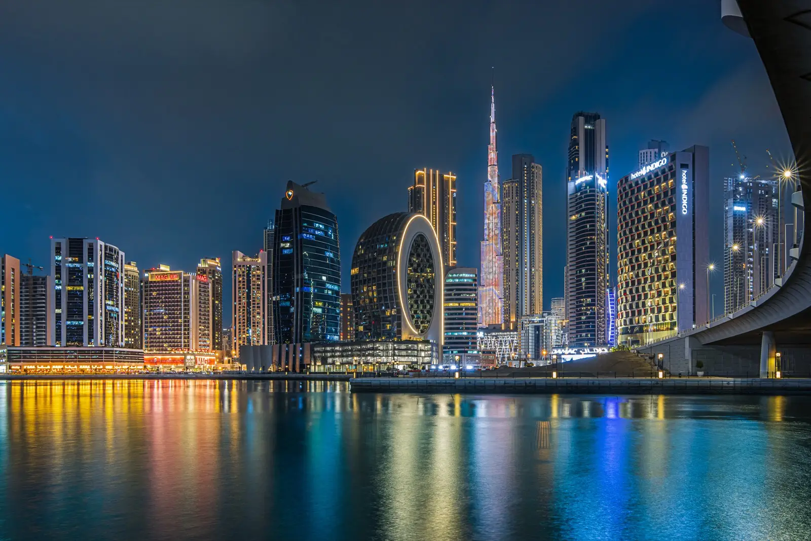 Dubai's Business Bay towers and the Burj Khalifa lit at night above still water, the city investors are reassessing this year